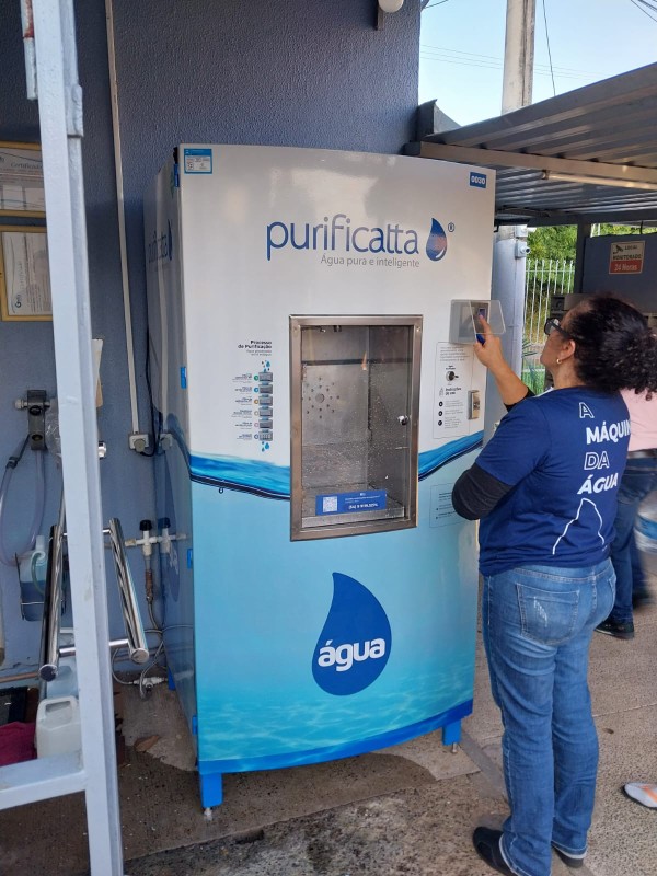 Moradora enchendo o galão na máquina Famiglia