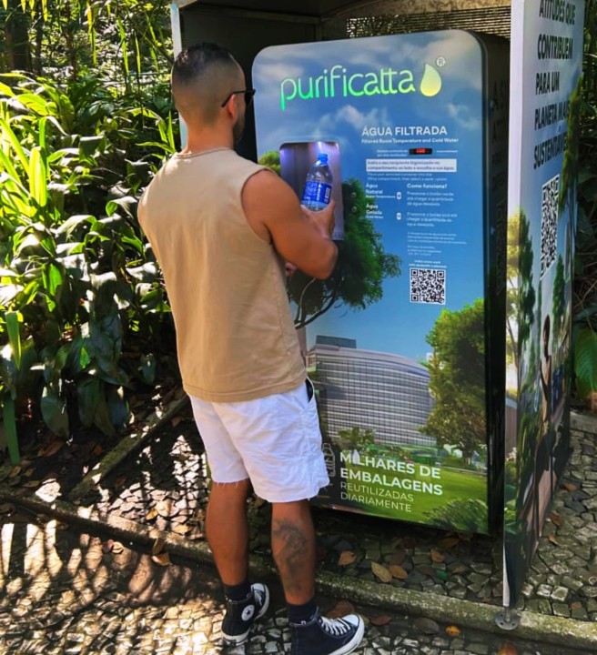 Homem enchendo a garrafa na máquina Purificatta em área verde
