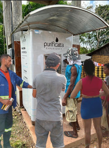 Moradores enchendo galões na máquina Comunitá